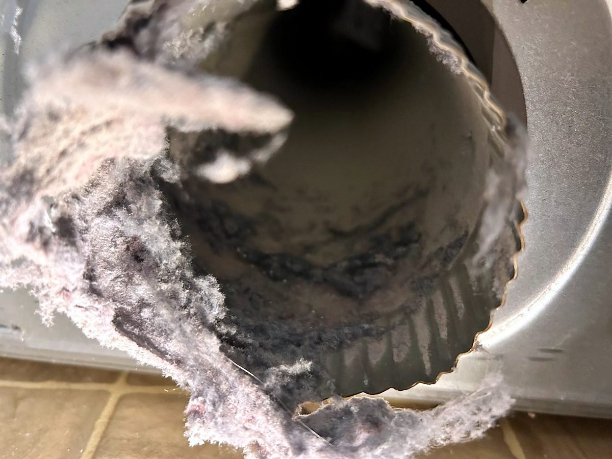 Dryer vent duct packed with gray lint before cleaning